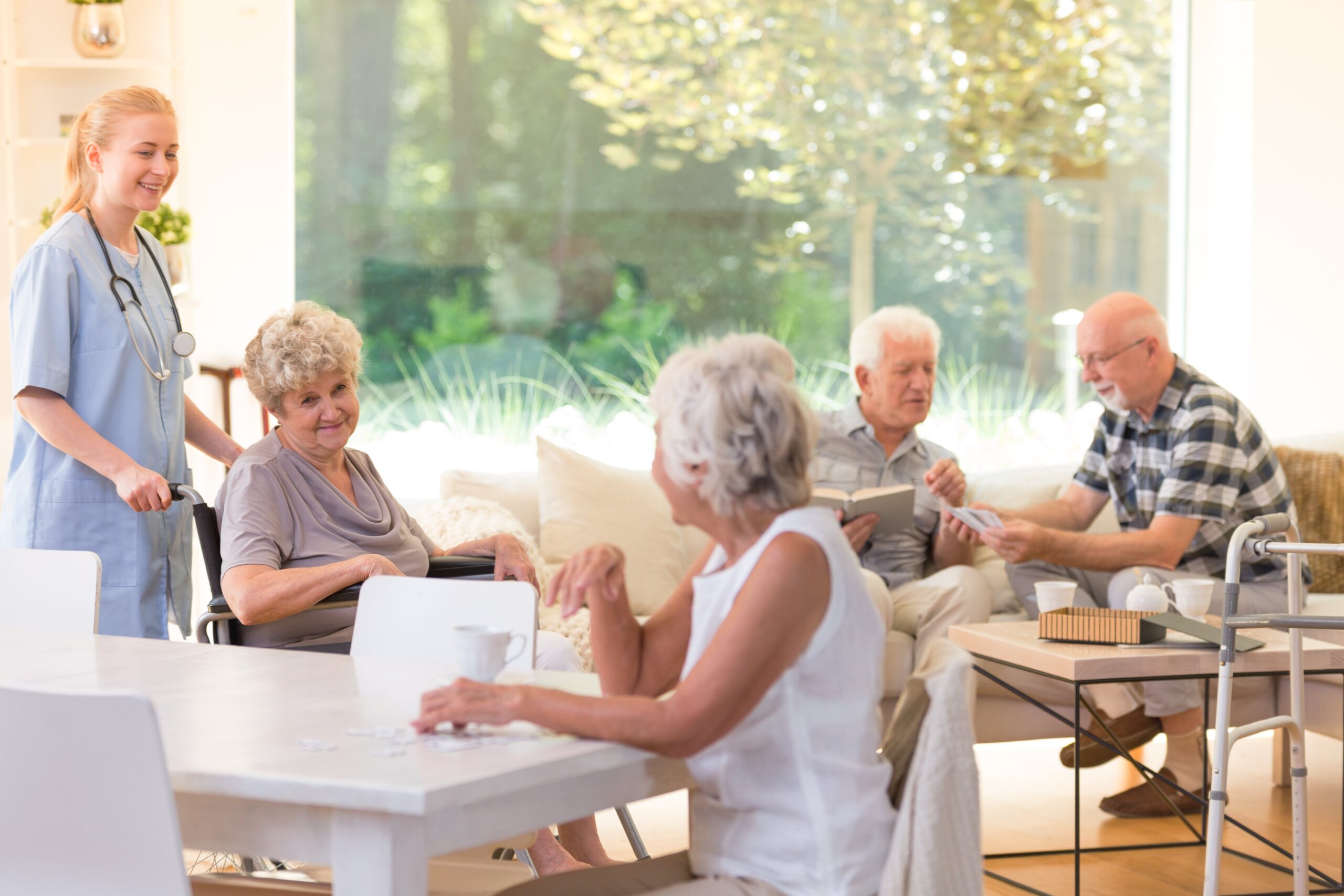 An image of a caretaker and seniors sitting around tables at an assisted living Tacoma facility.